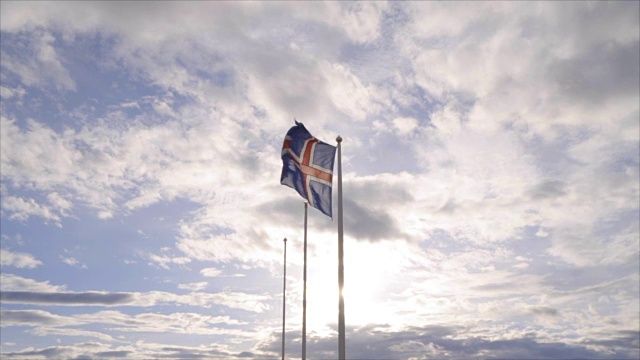 在日落时，冰岛国旗在天空和太阳下飘扬-慢动作视频-旅游目的地北欧国家的概念视频素材