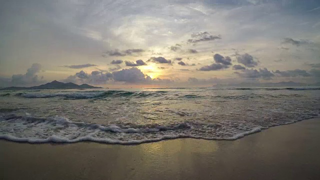 西班牙马略卡巴利阿里群岛阿尔库迪亚湾的4K马略卡Puerto de Alcudia海滩的日出。太阳在海中的山脉附近升起视频下载