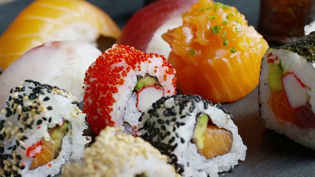 寿司，生鱼片，浦城和夜拍的微距镜头。典型的日本菜，包括米饭、鲑鱼或金枪鱼、虾和浸在酱油中的鱼卵。视频购买