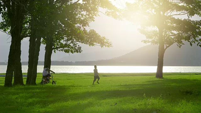 小男孩，两岁，7岁，喜欢在日落的草地上骑自行车和跑步，背景是自然，树木，河流和山。视频4k慢动作视频下载