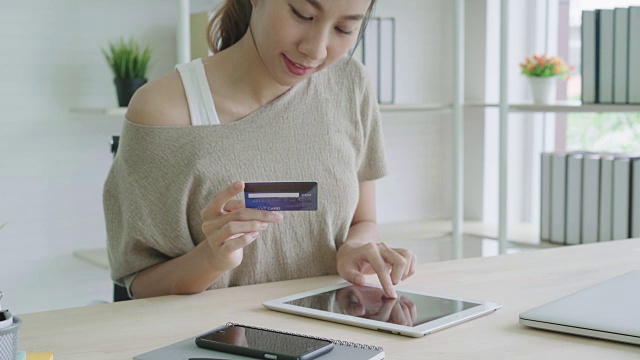 有魅力的亚洲女人用数字平板电脑支付信用卡。视频素材