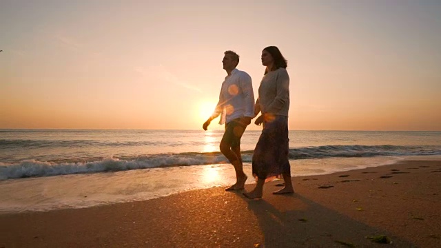 一对情侣在海滩上散步。视频下载