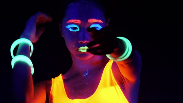 迷人的视频性感的网络raver女人拍摄在荧光衣服下的紫外线黑光。性感的女孩网络发光raver妇女拍摄在紫外线黑光下荧光服装，派对的概念视频素材