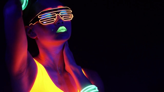 迷人的视频性感的网络raver女人拍摄在荧光衣服下的紫外线黑光。性感的女孩网络发光raver妇女拍摄在紫外线黑光下荧光服装，派对的概念视频下载