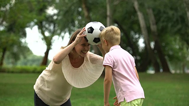 男孩和妈妈在公园踢足球，快乐的家庭周末，健康的生活方式视频素材