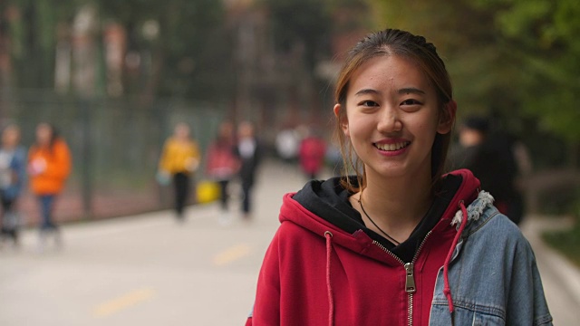 校园里年轻的亚洲女孩在镜头前微笑的肖像视频素材