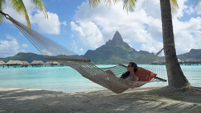 一名女子在热带岛屿度假胜地的吊床上休息。视频下载