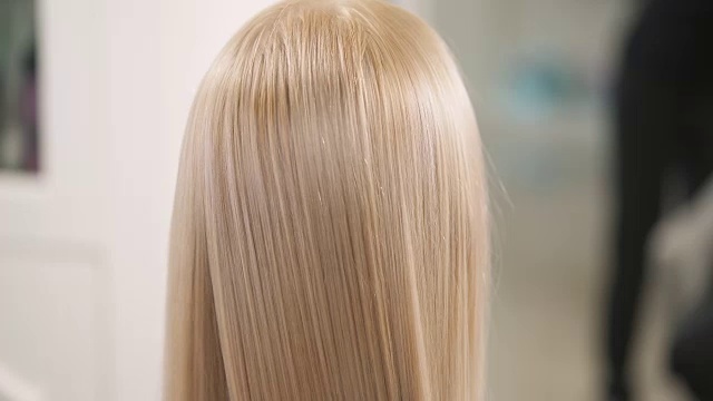 一个近距离的金发的头发梳由一个排气发刷长度。摄像机慢慢地上下移动。视频素材