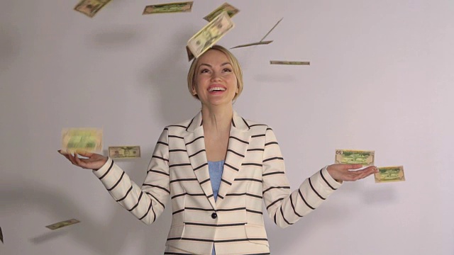 在白色的背景下，成功的女人站在钱下面的慢镜头视频素材