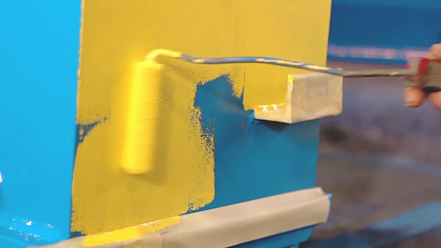 男子正在用手把蓝色的金属细节涂成黄色视频素材