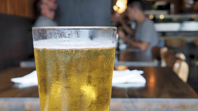 餐厅里，人们在用餐时，一杯刚倒好的淡啤酒在杯顶冒泡视频素材