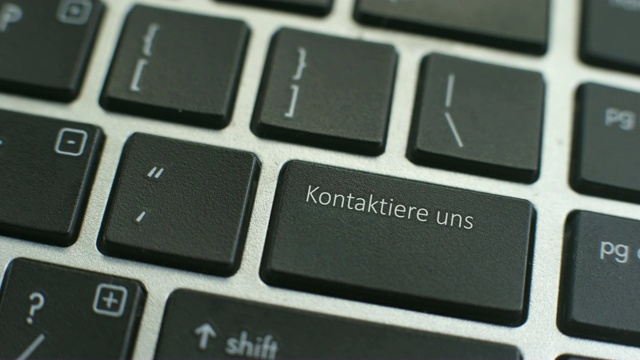 联系我们用德语在电脑键盘上按按钮，女性的手手指按下按键视频素材