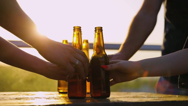 朋友们在户外喝啤酒。瓶子在手中特写视频下载