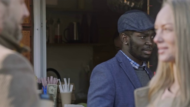 一个年轻人在街上的食品摊上买咖啡视频素材
