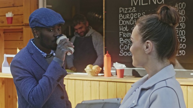 一个严肃的非裔美国人在咖啡店附近听一个黑发白种女孩的演讲视频素材