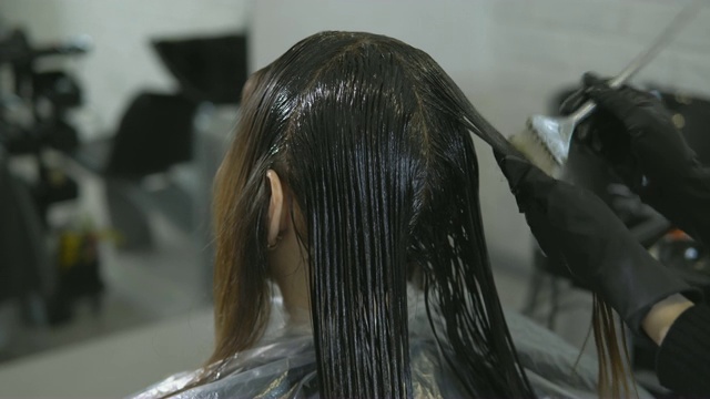 发型师在美容院为一位年轻女子画头发，特写。视频下载