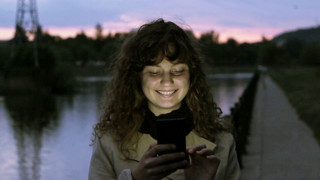 年轻女子用智能手机微笑。视频下载