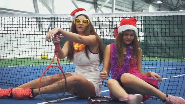 两名网球运动员戴着新年装饰品坐在网球场上视频素材