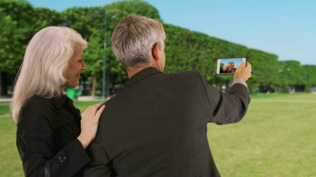巴黎一对成熟的夫妇在看他们智能手机上的照片视频素材