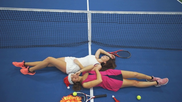 两个有趣的女孩躺在网球场上视频素材