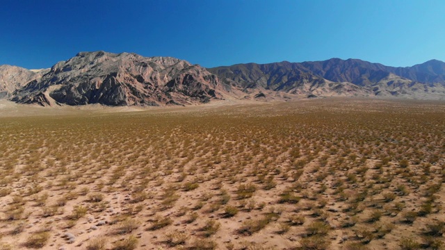 卡车前进无人机拍摄的一个沙漠平原在犹他州与山脉背景下的晴朗，蓝天视频下载