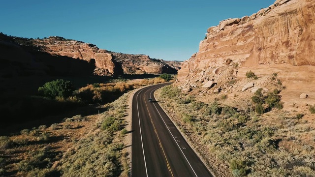 镜头跟随汽车行驶在高速公路上，巨大的陡峭的阳光峡谷山覆盖着沙子和岩石。视频素材