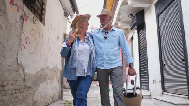 一对可爱的老年夫妇走过城市街道，四处张望视频素材