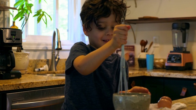 微笑的小男孩和父亲在厨房一起做炒鸡蛋视频素材