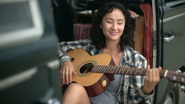 年轻女子在露营车里弹吉他视频购买