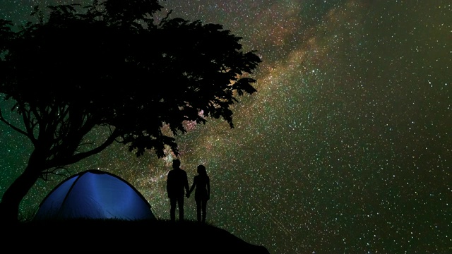 这对情侣站在一个露营帐篷附近，背景是星空。时间流逝视频素材