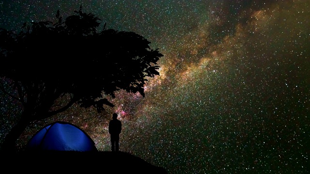 那个人站在山上，树对着星空。时间流逝视频素材