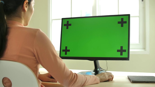 近距离拍摄的年轻亚洲妇女使用电脑与绿色屏幕在现代的家视频下载