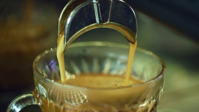 特写镜头:浓缩咖啡倒进一个装饰玻璃杯子里，然后有人把它拿起来视频素材