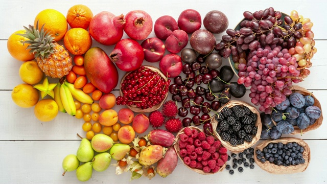 白色的桌子上摆满了五颜六色的水果。新鲜果汁和冰沙成分。健康饮食理念。视频下载