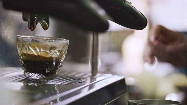 一个女人放下蒸牛奶，擦干净她的浓缩咖啡机，把浓缩咖啡倒入咖啡杯视频素材
