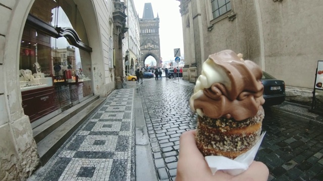 捷克布拉格，一名游客拿着trdelnik冰淇淋蛋卷走在鹅卵石小巷里视频下载