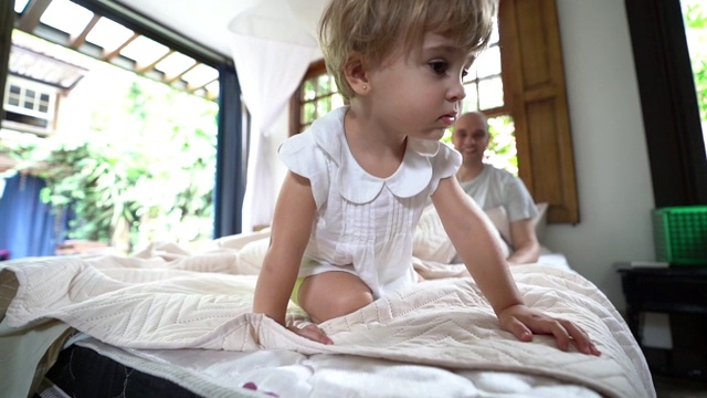 父母与可爱的女儿在床上玩得开心视频素材