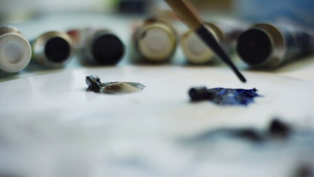 一个艺术家在调色板上用小画笔蘸着蓝色油画颜料视频素材