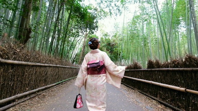 4K的后续镜头:一名身穿和服的亚洲女子走过岚山竹林和佐野竹林。日本文化视频下载