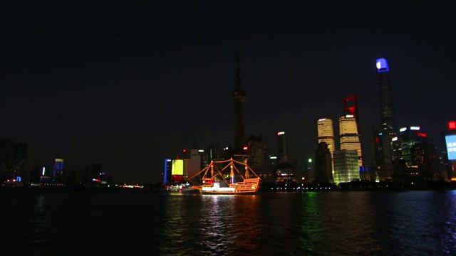 在上海黄浦江上，一艘灯火通明的船从外滩眺望浦东天际线视频素材