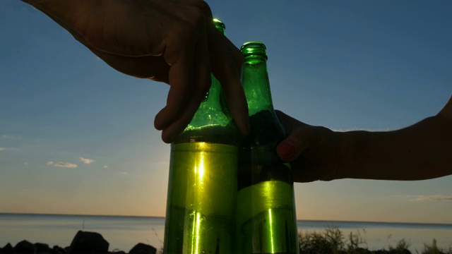 近距离的手在日落的啤酒瓶敬酒视频素材