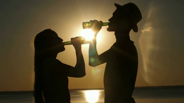 日落时分喝啤酒的情侣剪影视频素材