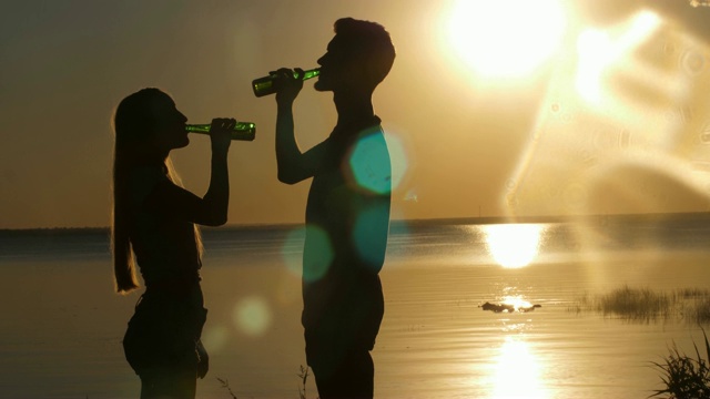 快乐的朋友在海滩上喝啤酒的剪影视频素材