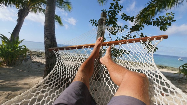 一名男子在热带岛屿上的吊床上放松。——慢动作视频下载