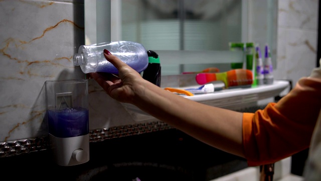女人把肥皂液从瓶子里倒进浴室的自动售货机里视频素材