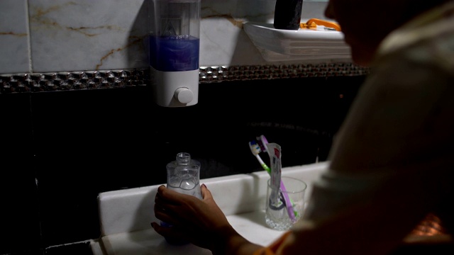 女人把洗澡间里的肥皂液倒进瓶子里视频素材