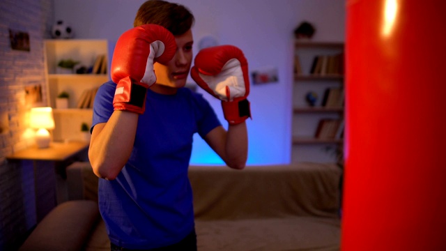 少年戴着手套出拳拳击袋，梦想成为拳击手，健身视频下载