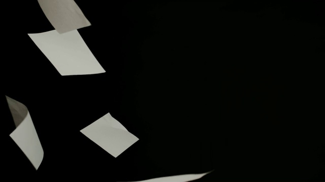 一張張白紙以慢鏡頭落在黑色的背景上。視頻下載