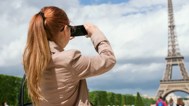 一名女子在战神广场花园用智能手机拍摄埃菲尔铁塔视频素材