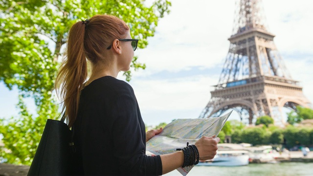女游客探索巴黎地图，从塞纳河对面看埃菲尔铁塔视频素材